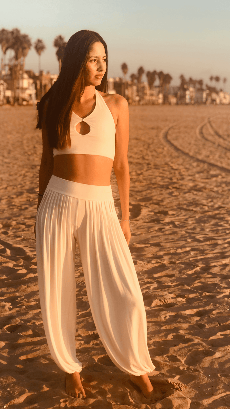 Girl wearing white parachute flowy pants with white halter top at Venice Beach