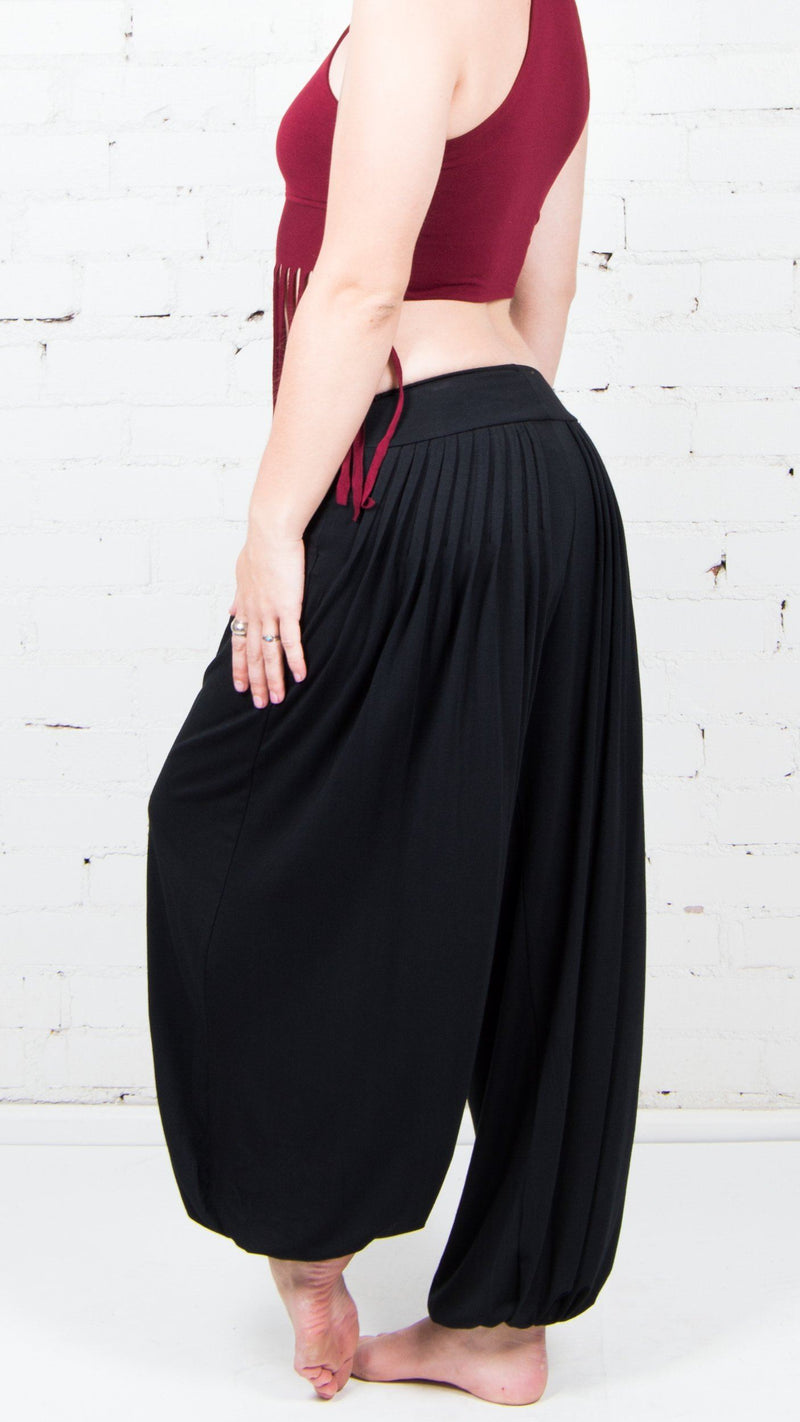 side view of female model wearing black dance pants, wine colored fringe crop top 